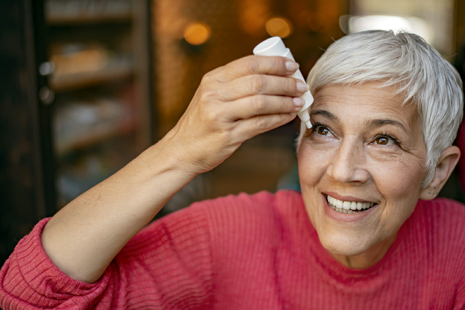Photo of senior woman putting eye drop, closeup view of elderly person using bottle of eyedrops in her eyes. Sick old woman suffering from irritated eye, optical symptoms. Health concept. Concept of eye treatment, vision improvement, poor eyesight