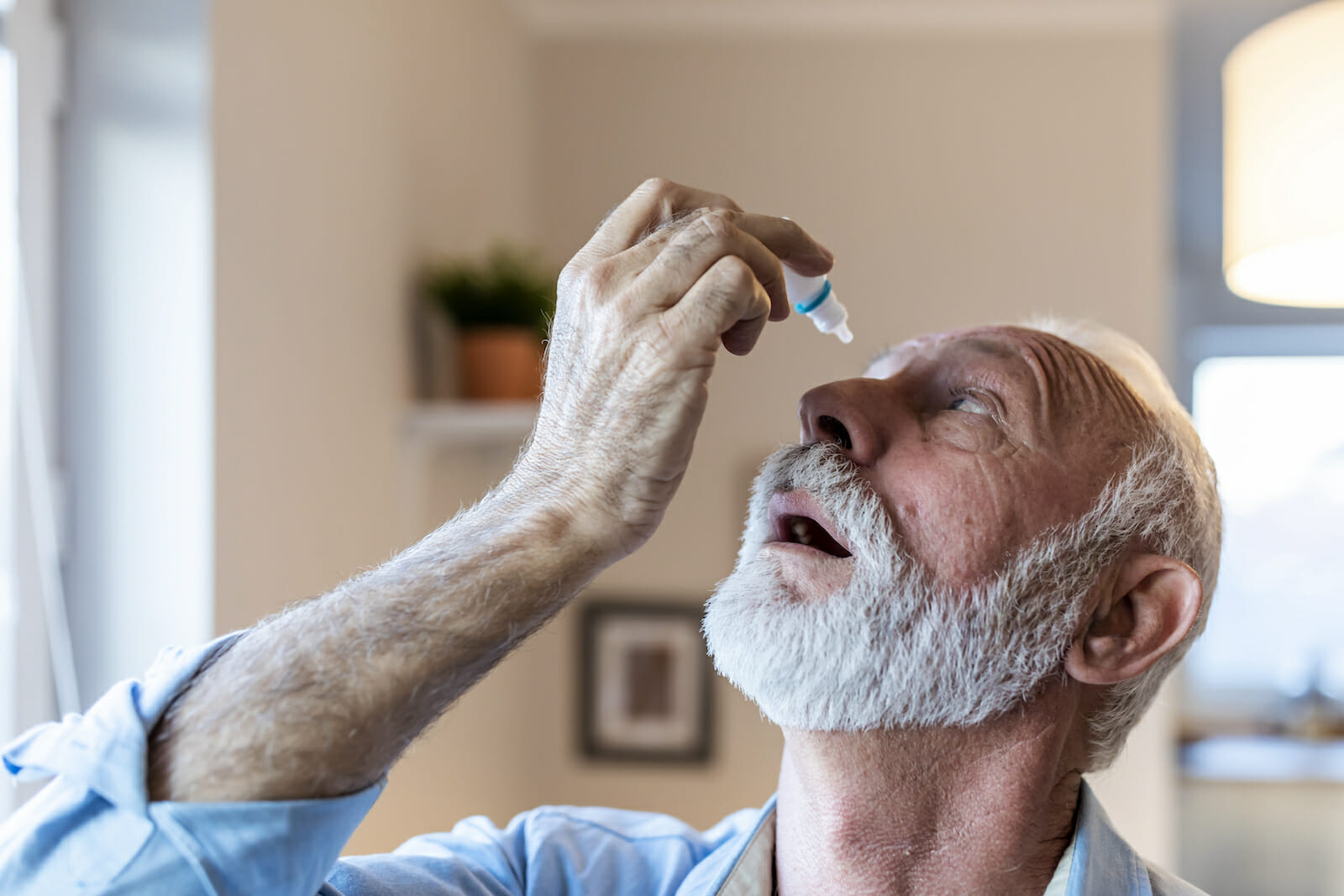 Man using eye drops for glaucoma