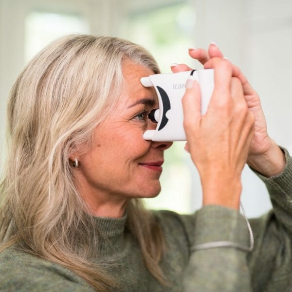 Picture of a woman with glaucoma using the iCare Home tonometer to measure her eye pressure