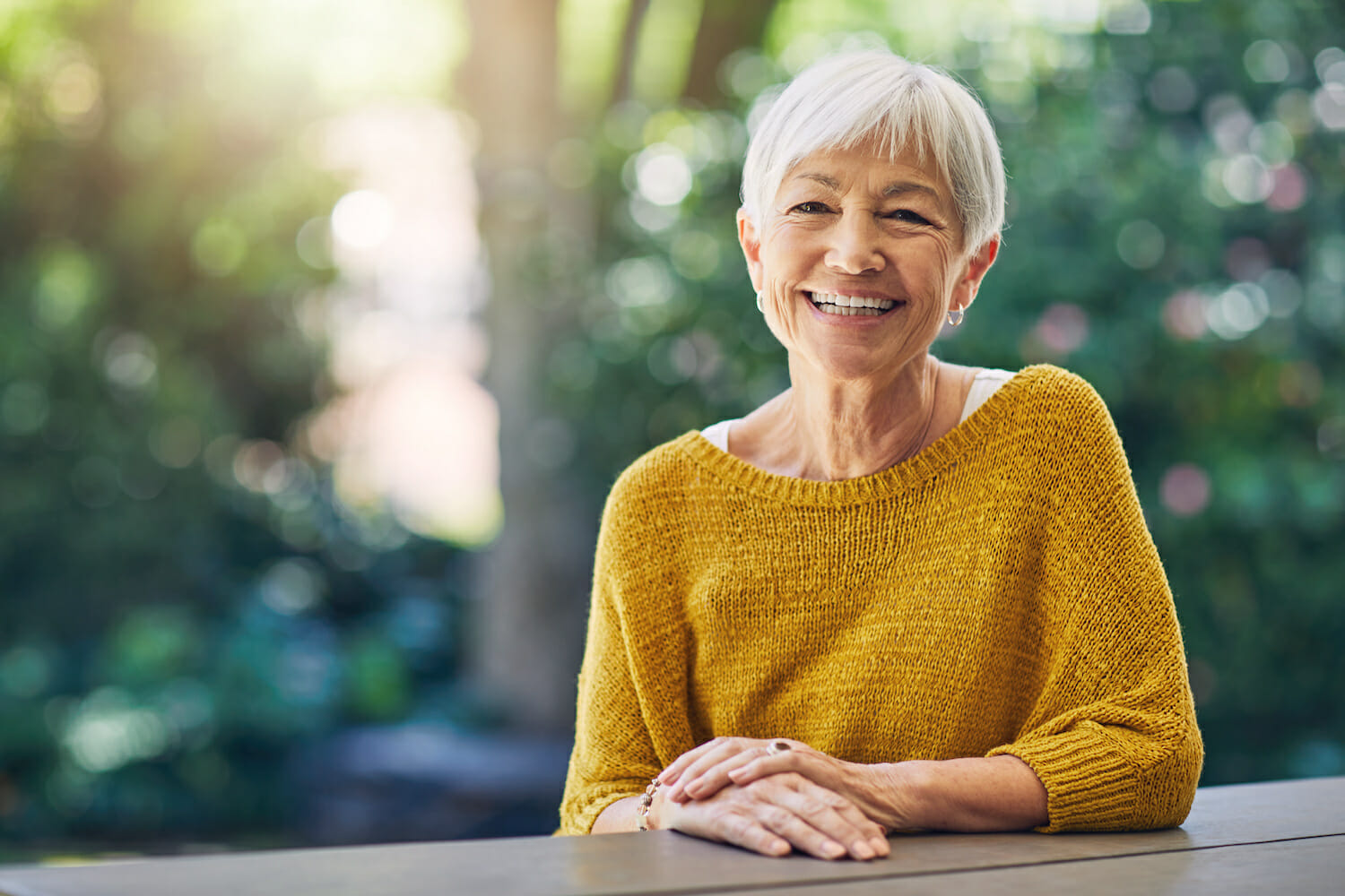 Shot of a happy senior woman sitting at a table in her backyard